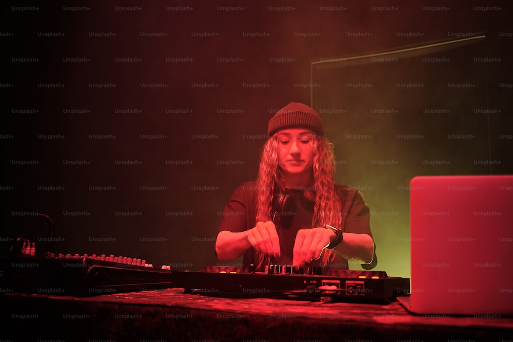 a woman in a black hat is playing a dj set