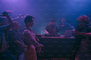 a group of people standing around a dj booth