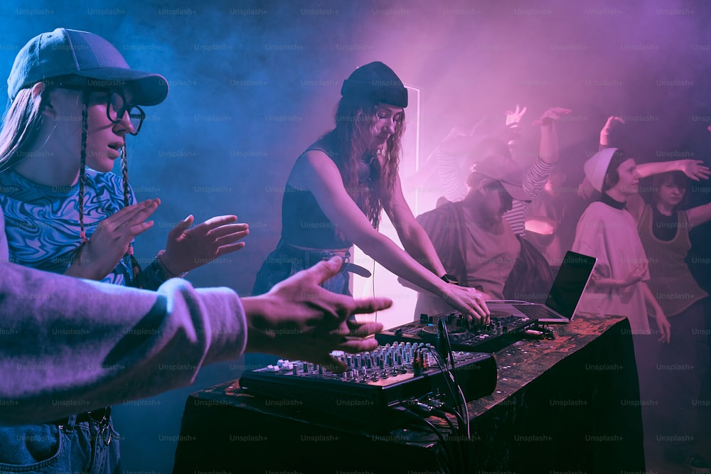 Um grupo de pessoas em pé ao redor de uma cabine de DJ