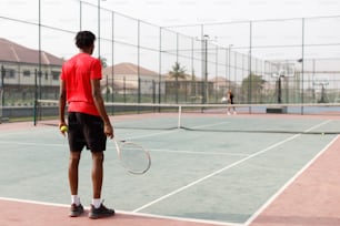 Un hombre de pie en una cancha de tenis sosteniendo una raqueta