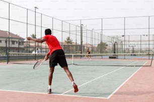 Un uomo in maglietta rossa sta giocando a tennis