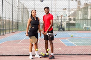 un uomo e una donna in piedi su un campo da tennis con racchette