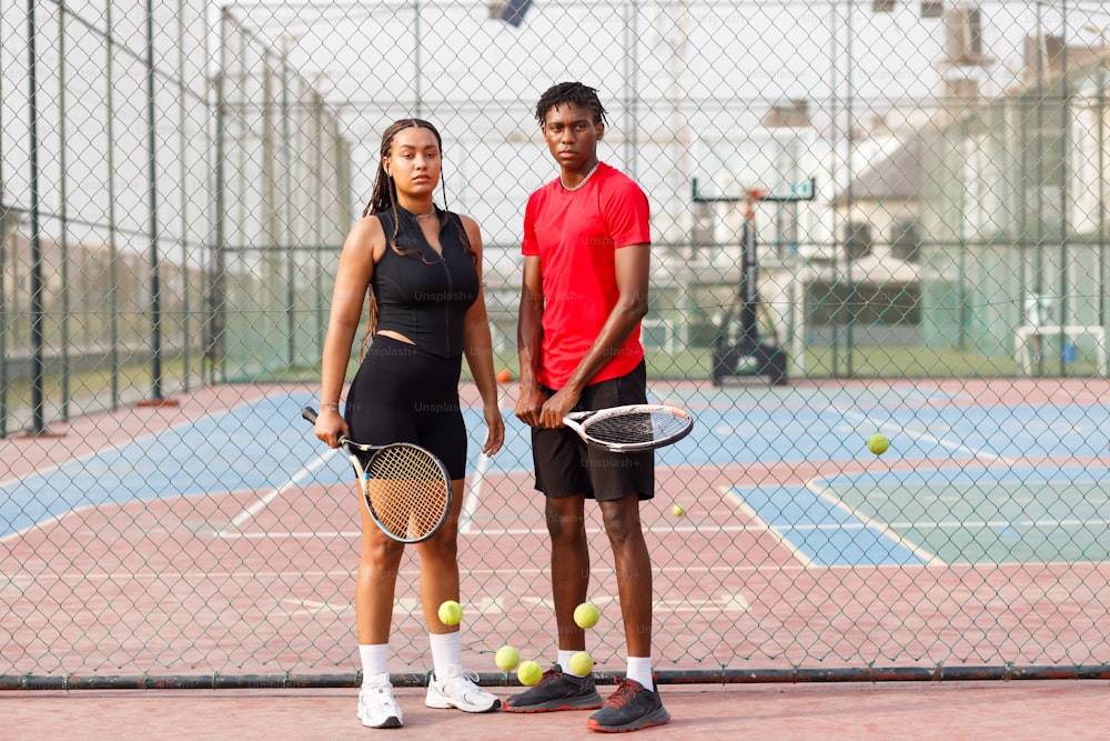 a man and a woman standing on a tennis court holding racquets
