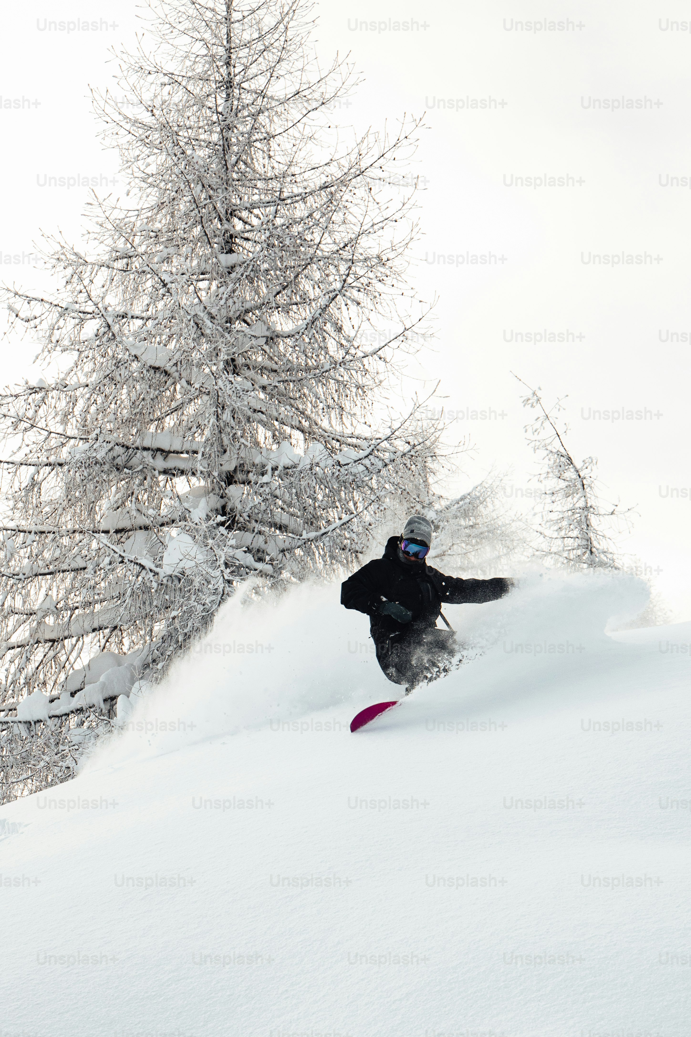 Un hombre montando una tabla de snowboard por una pendiente cubierta de nieve