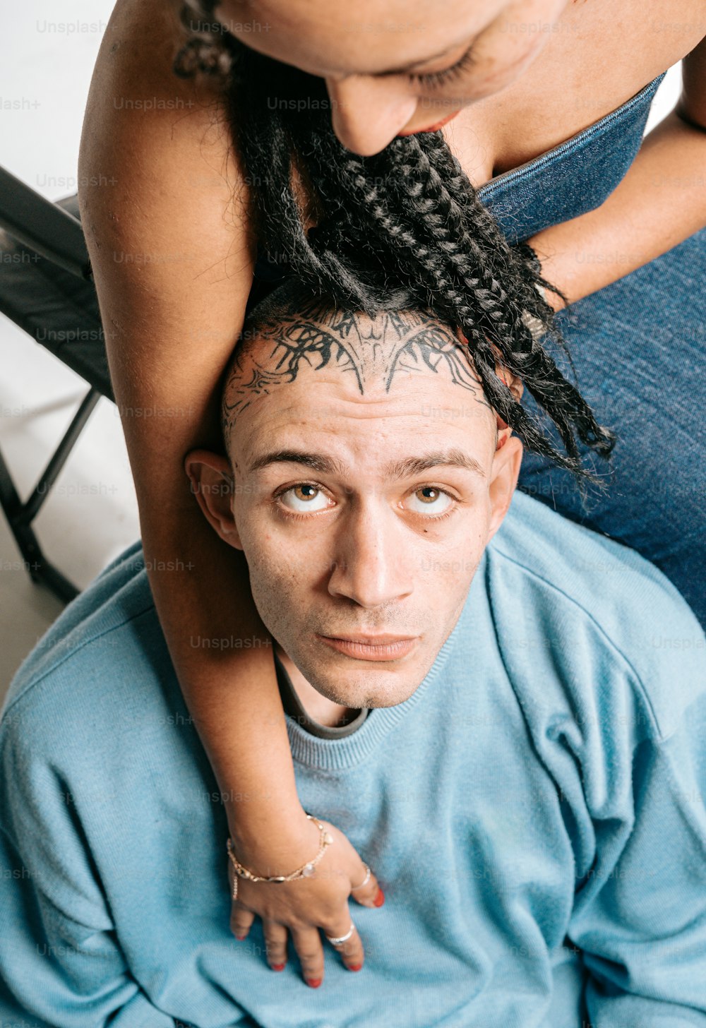 una mujer sosteniendo la cabeza de un hombre mientras ambos tienen tatuajes en la cara