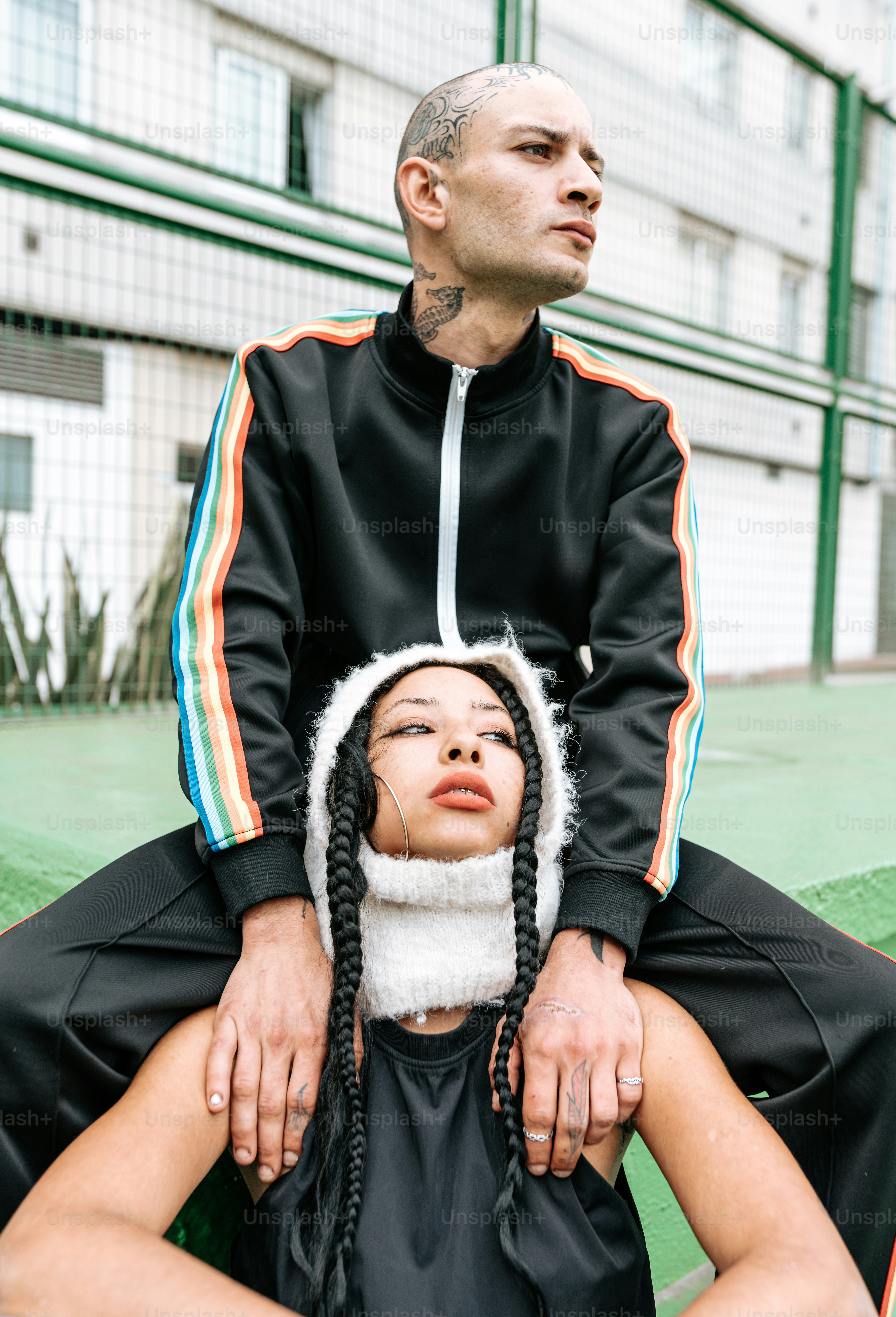 A man and a woman walking in front of an orange wall photo – Fashion ...