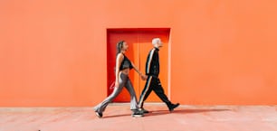 주황색 벽 앞을 걷고 있는 남자와 여자