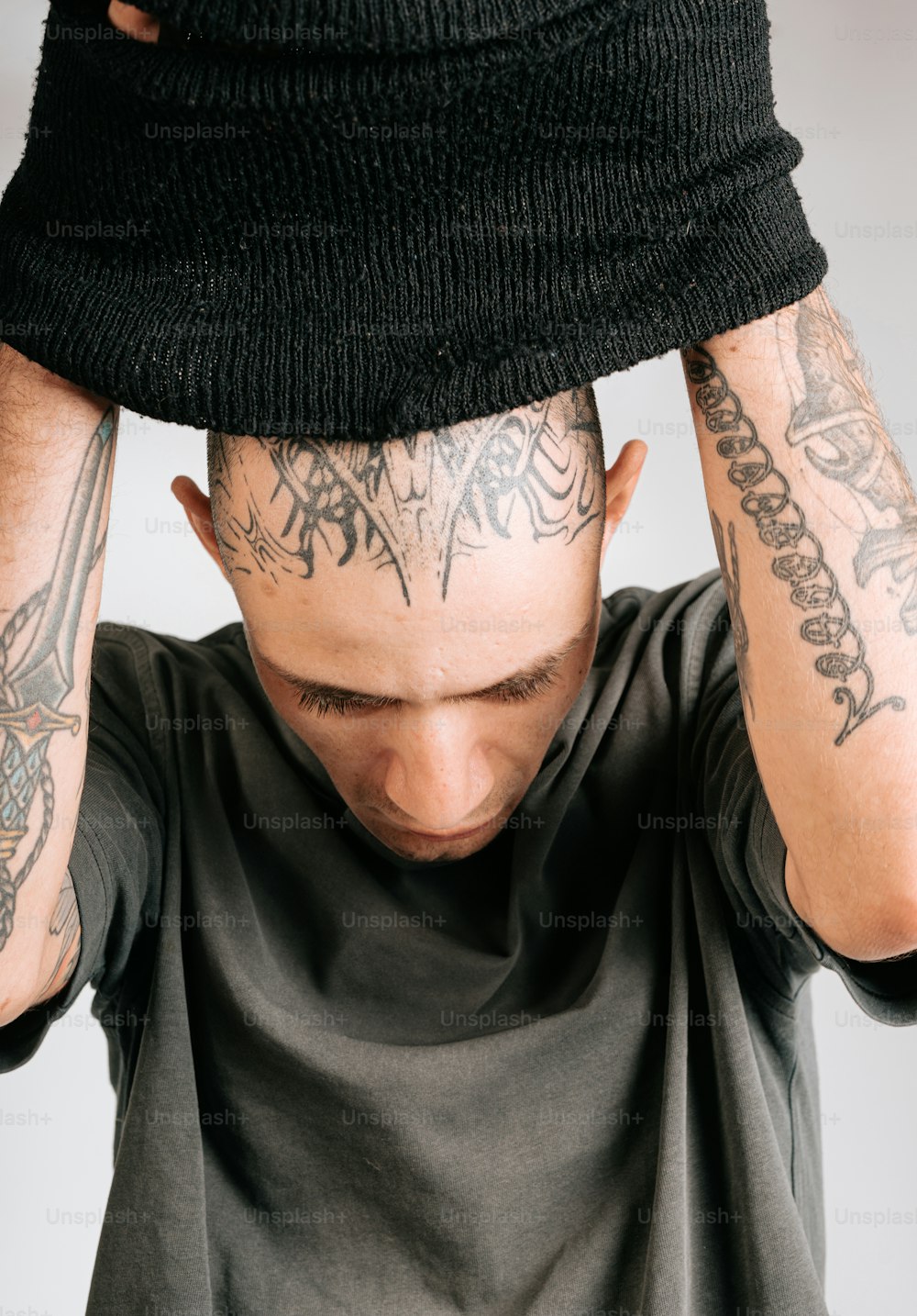 a man with tattoos covering his head with his hands