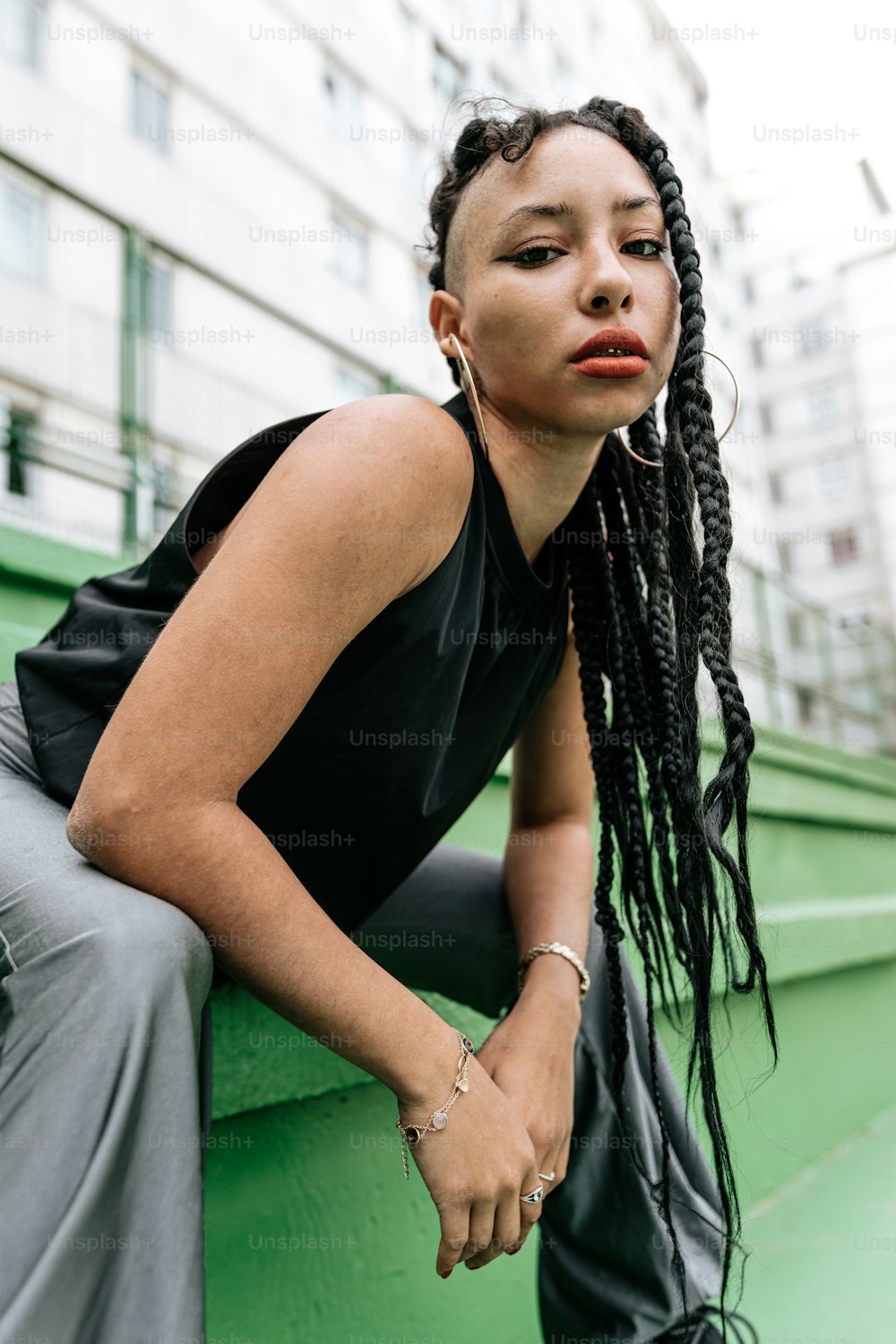 a woman with dreadlocks leaning against a green wall