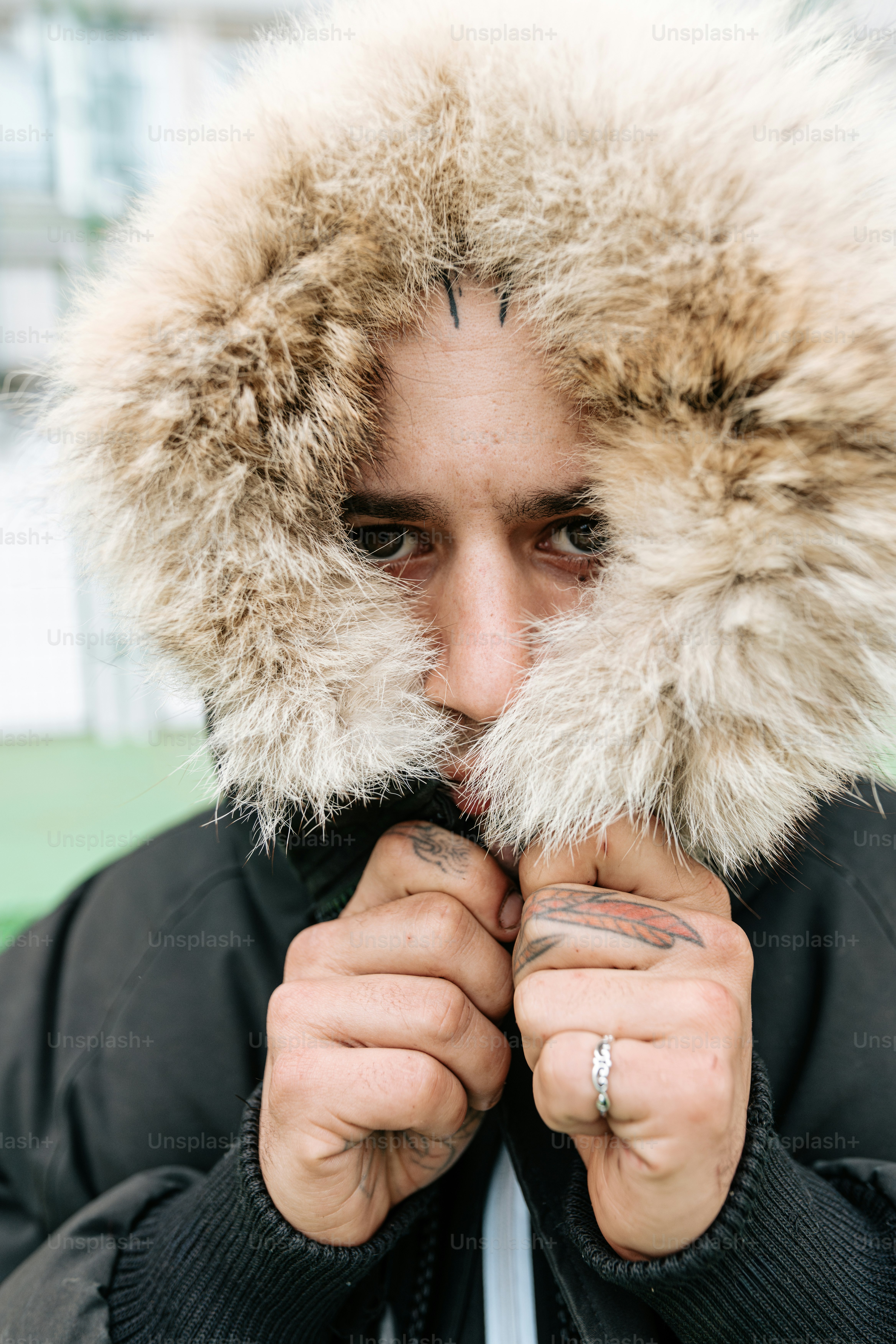 A man in a parka is covering his face with his hands photo – Portrait ...