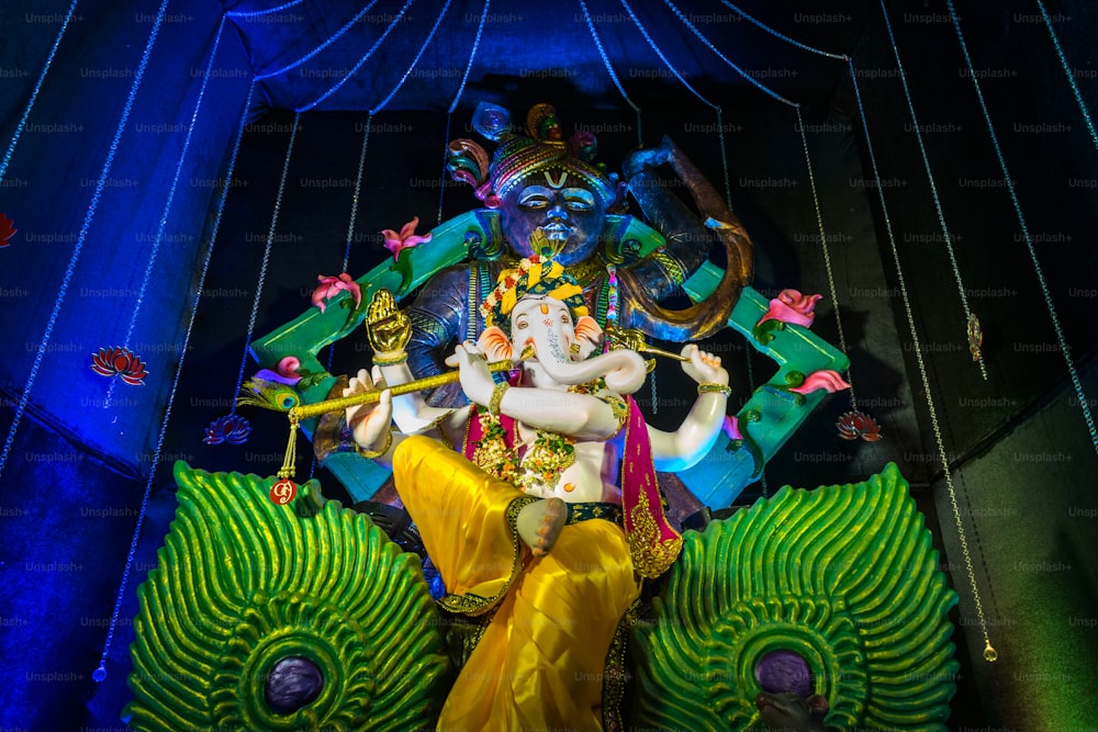 a statue of a hindu god sitting on top of a peacock