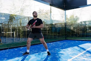 Un hombre de pie en una cancha de tenis sosteniendo una raqueta