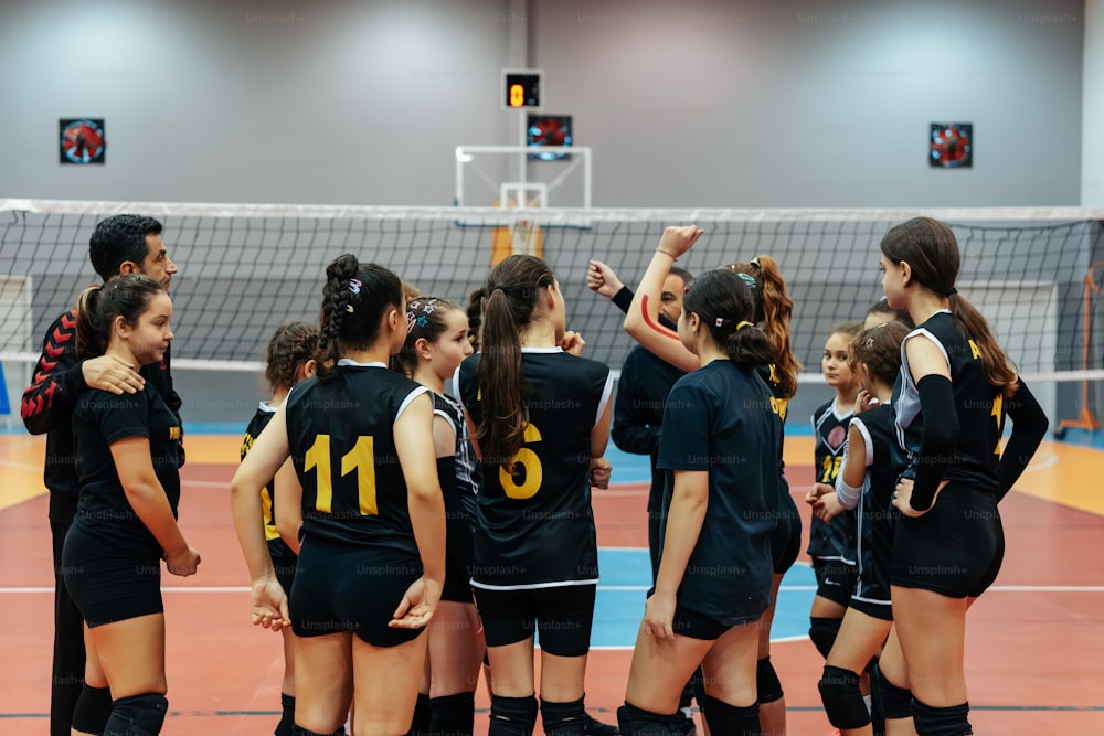 a group of young women standing next to each other on a volleyball court