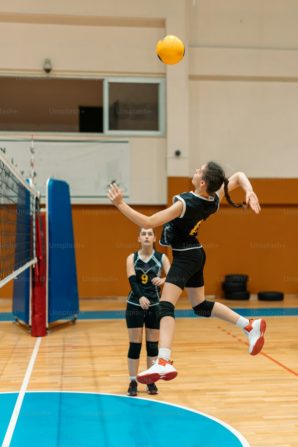 a woman jumping up to hit a volley ball