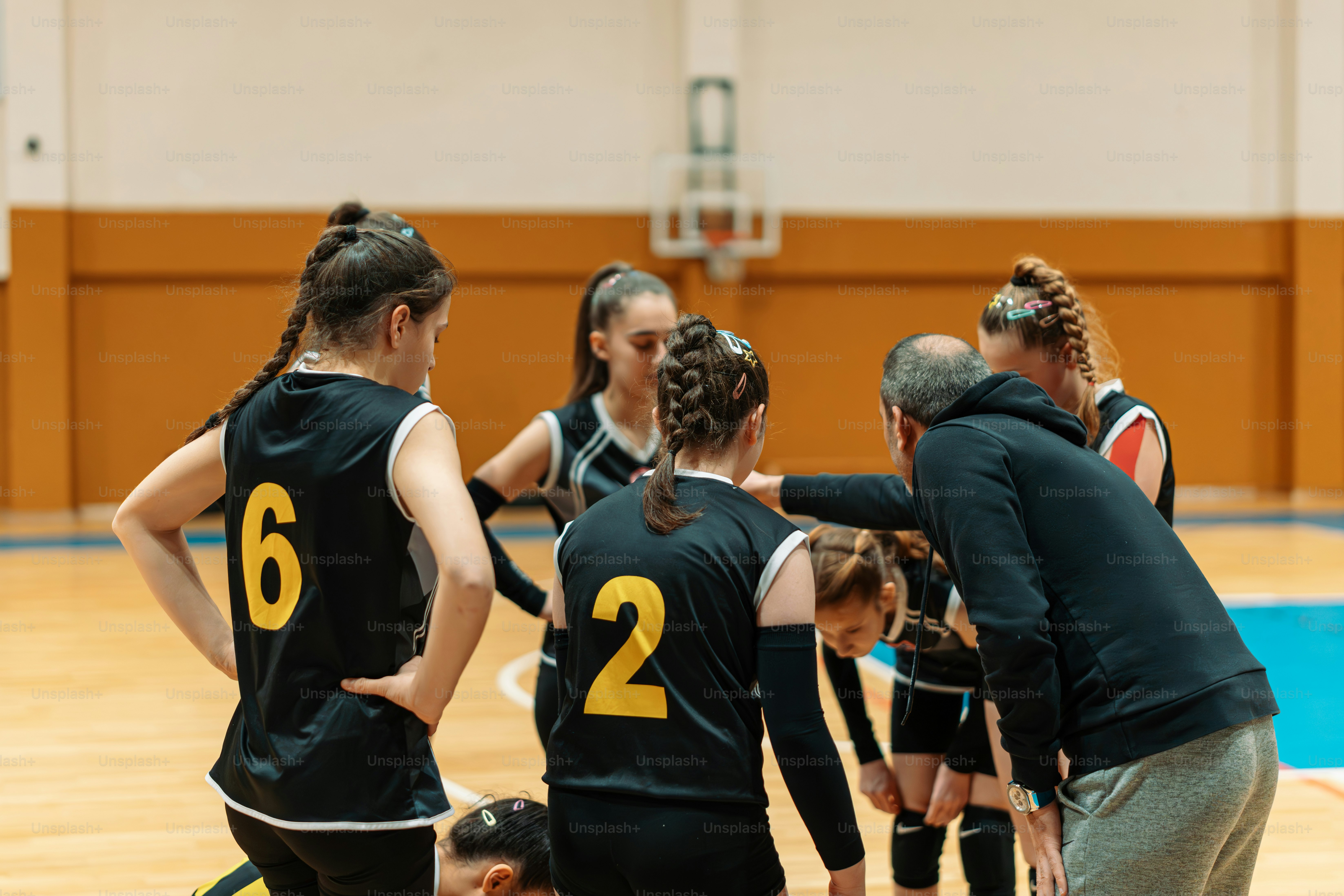 a group of young women standing on top of a basketball court