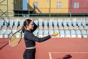 uma mulher segurando uma bola de tênis e raquete
