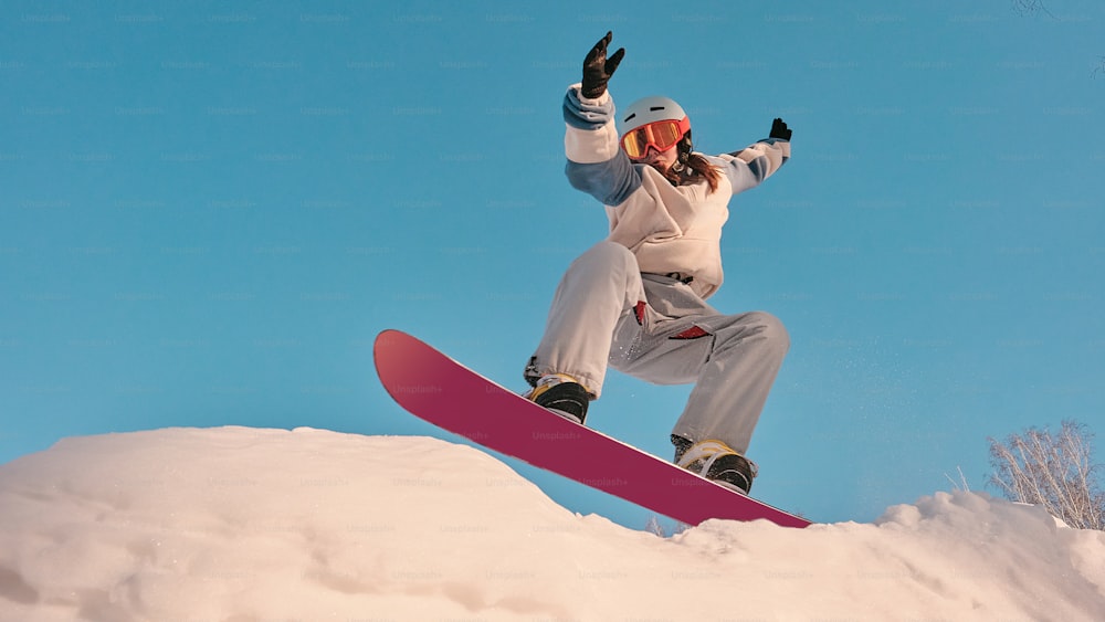 uma pessoa montando um snowboard em uma superfície nevada