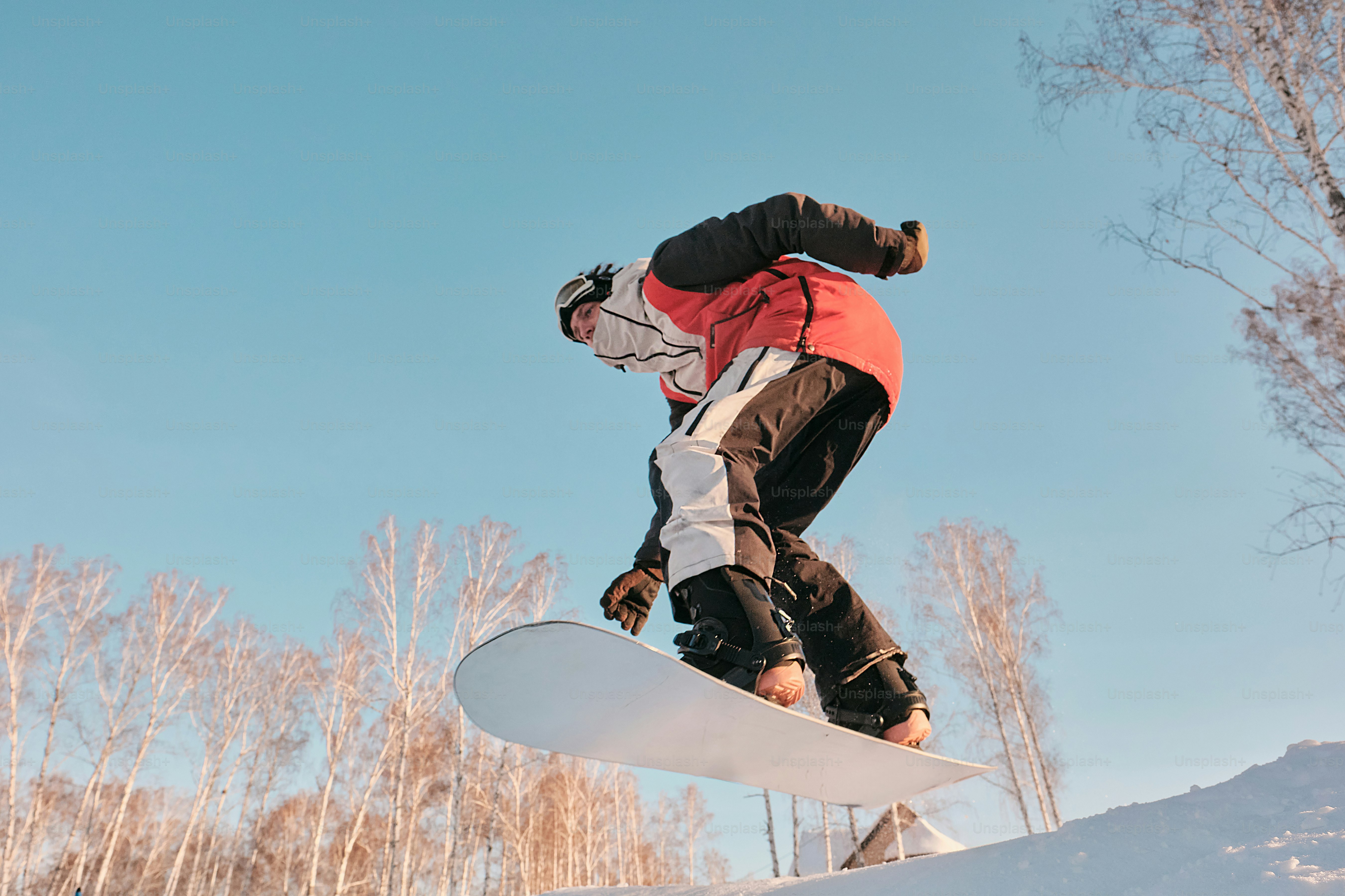 Ein Mann, der mit einem Snowboard die Seite eines schneebedeckten Hangs hinunterfährt