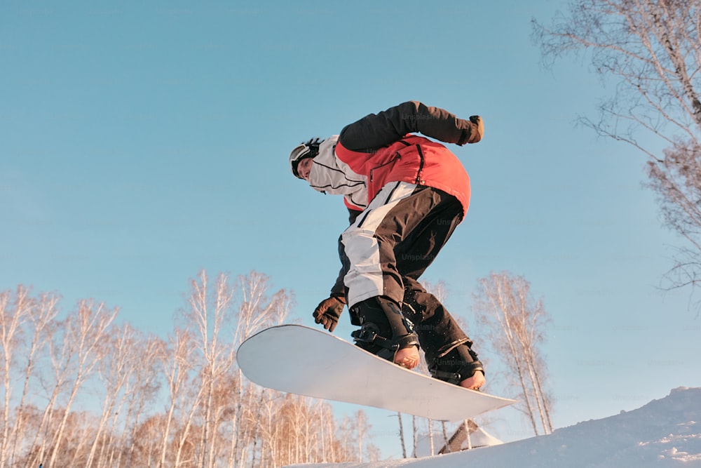 um homem montando um snowboard ao lado de uma encosta coberta de neve