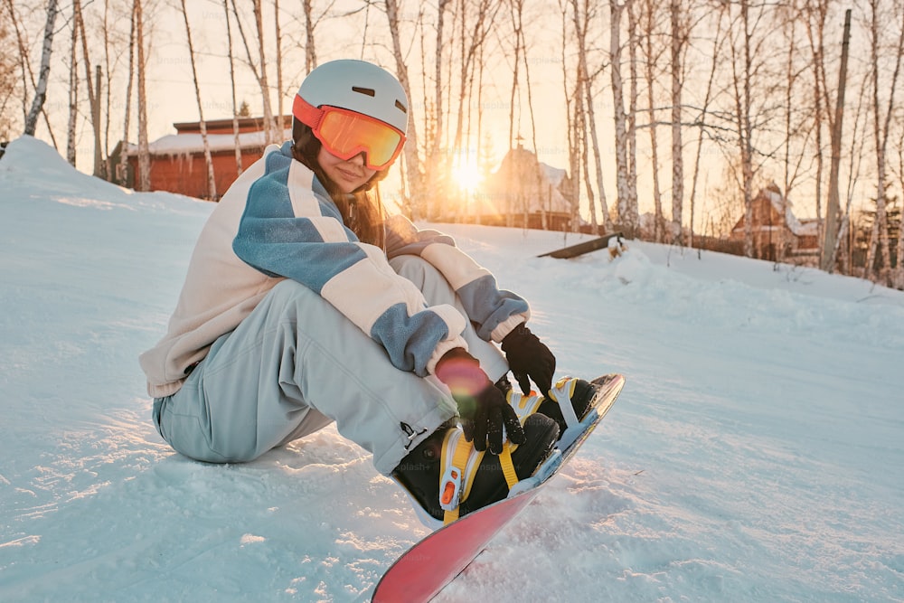 una persona sentada en la nieve con una tabla de snowboard