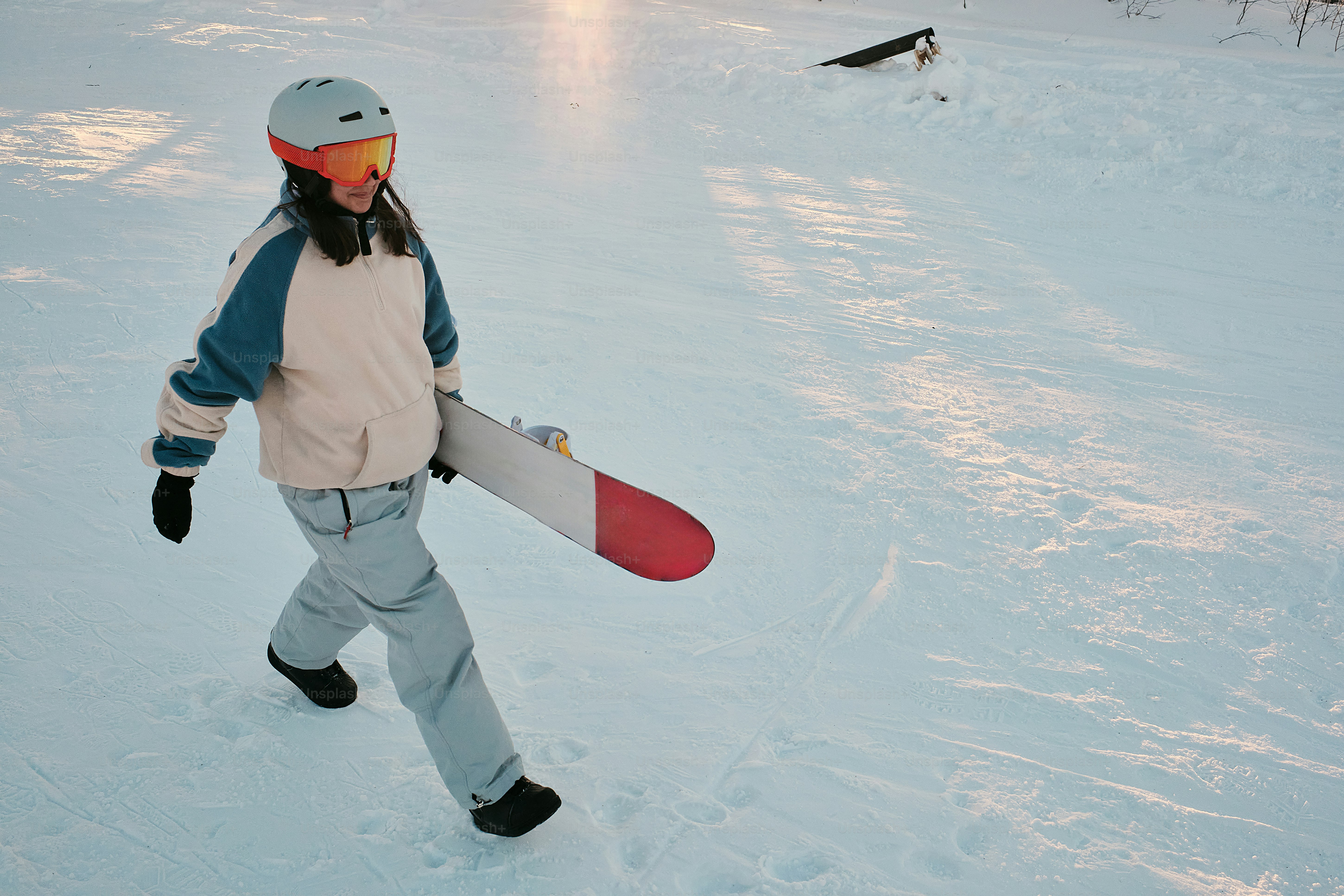 una persona che cammina nella neve portando uno snowboard