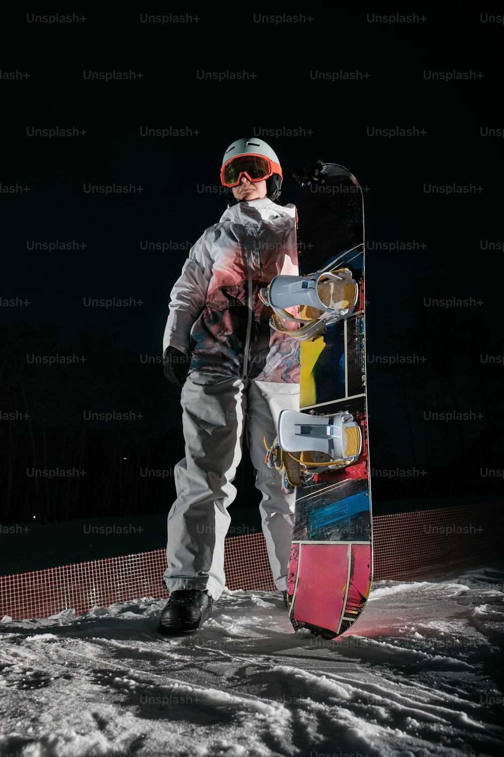 um homem segurando uma prancha de snowboard no topo de uma encosta coberta de neve