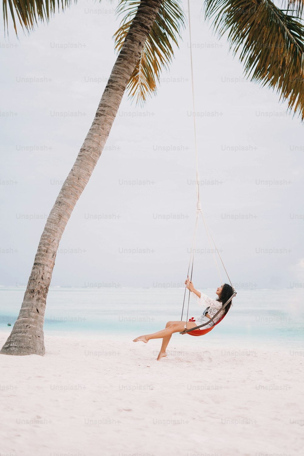 eine Frau sitzt in einer Hängematte am Strand