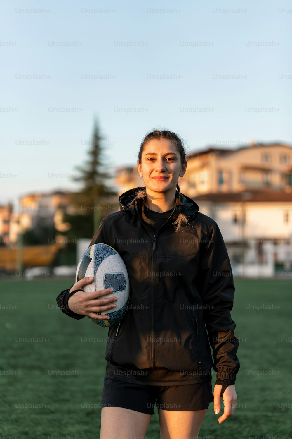 una mujer sosteniendo una pelota de fútbol en un campo
