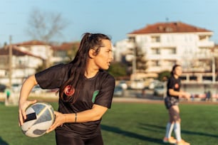 a woman holding a soccer ball on top of a field