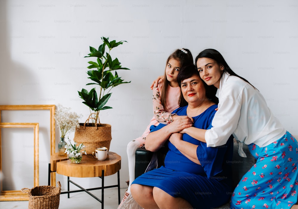three women sitting on a couch with a plant in the corner