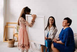 a woman and two girls sitting on a couch with a white board in front of