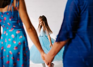 a little girl in a blue dress holding hands with a man in a blue dress