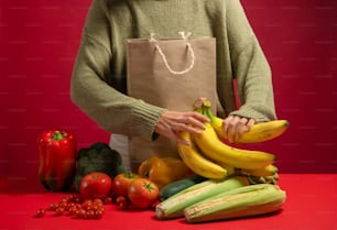 a person holding a bag over a pile of fruit and vegetables