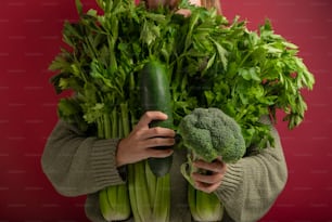 a woman holding a bunch of green vegetables
