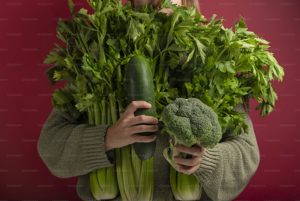 a woman holding a bunch of green vegetables