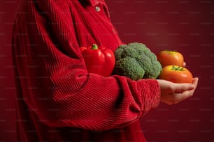 a person in a red sweater holding a bunch of vegetables