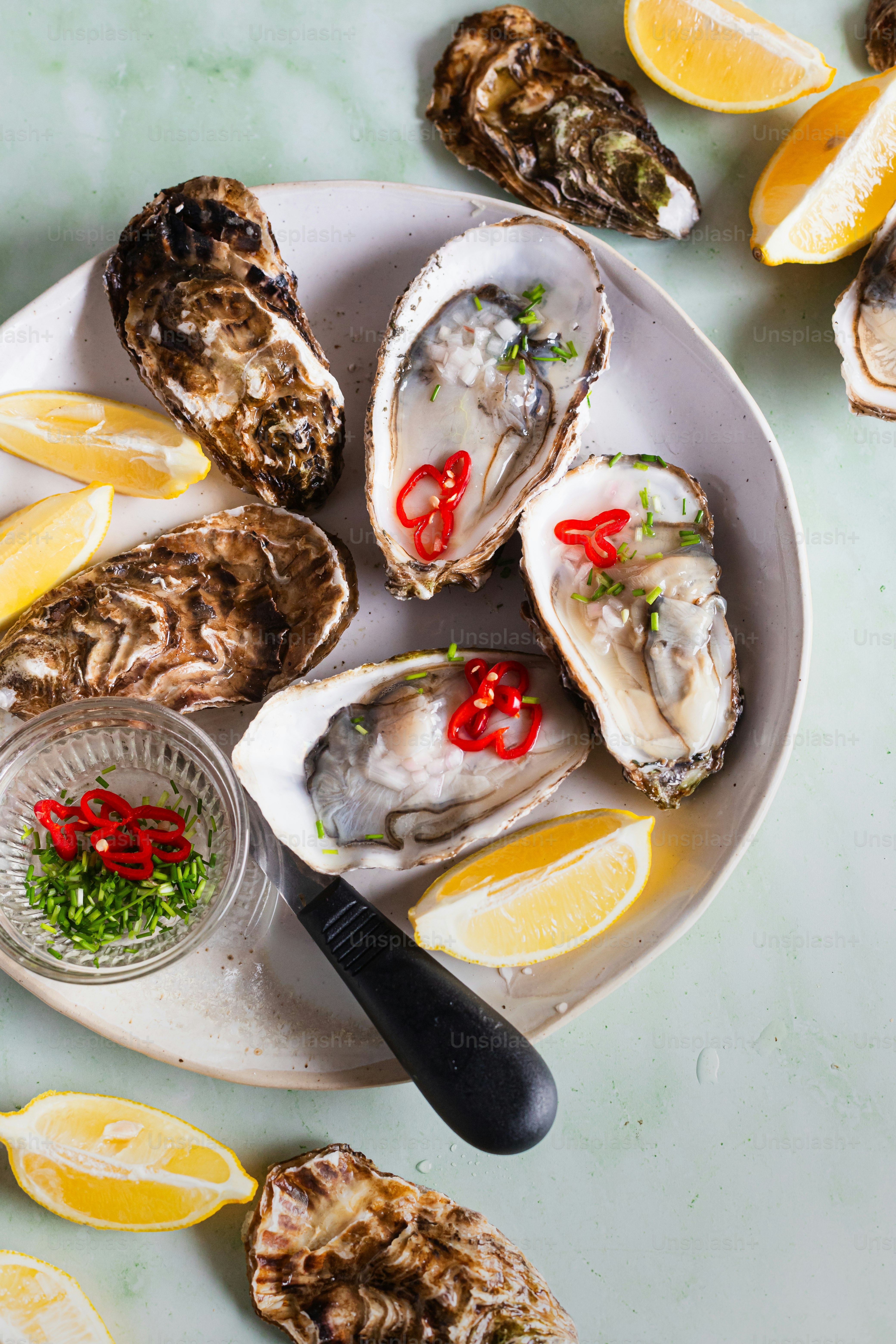 a white plate topped with oysters next to lemon wedges