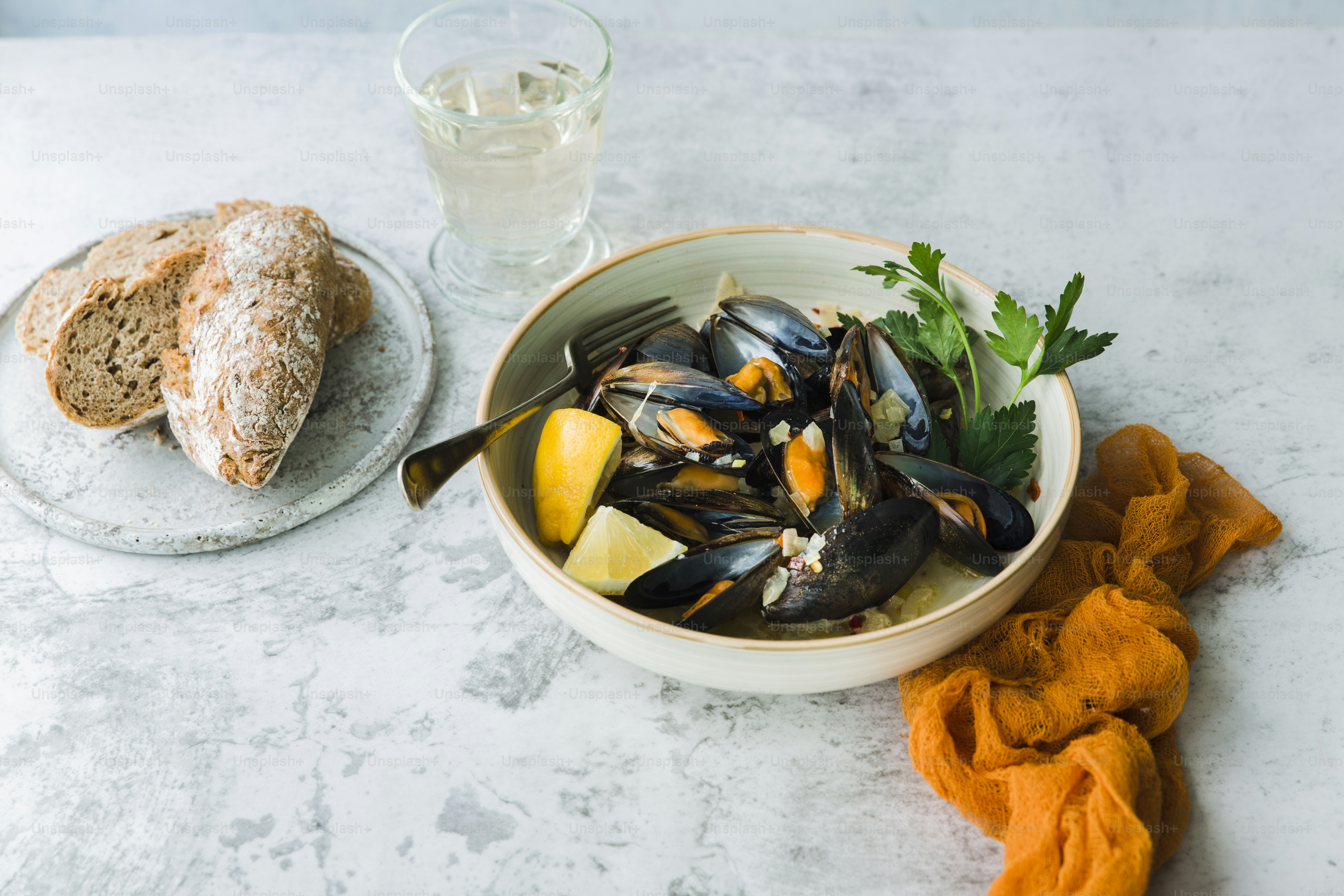 eine Schüssel mit Muscheln neben einem Glas Wasser