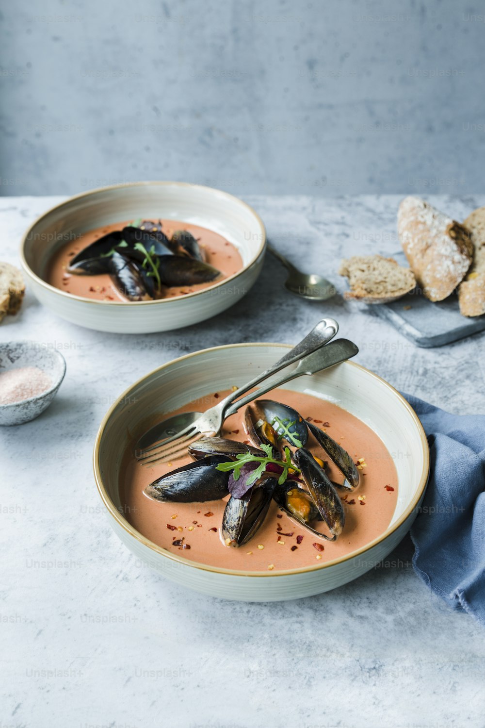 a bowl of soup with mussels and a spoon
