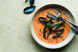a bowl of soup with mussels and garnishes