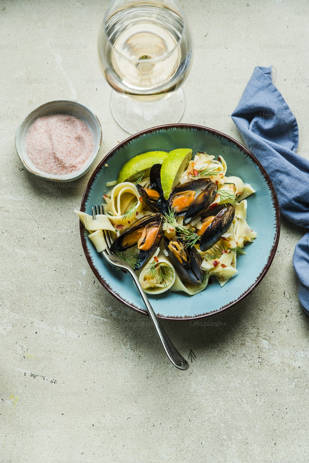 a plate of pasta with mussels and lemon wedges