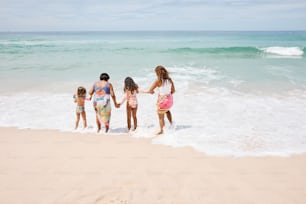 um grupo de meninas em pé no topo de uma praia de areia