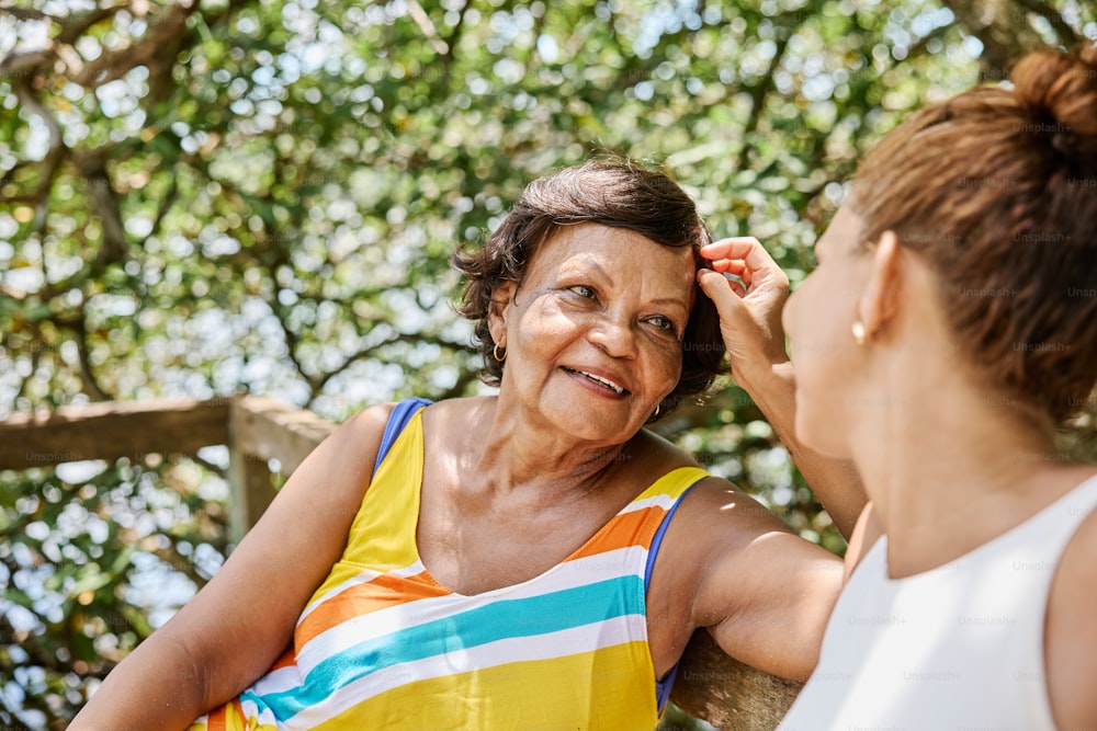 a woman combing another woman's hair in front of a tree