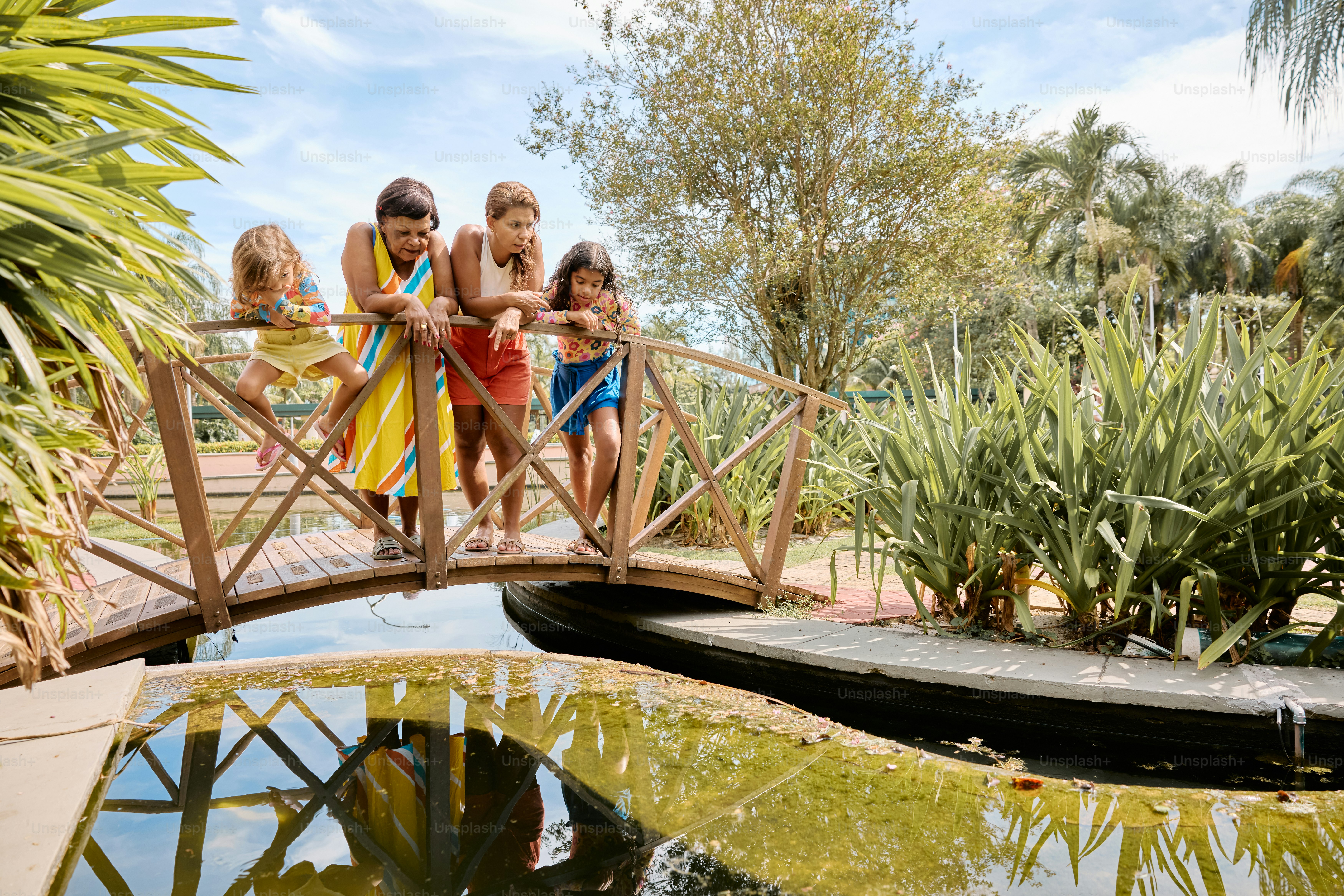 a group of children standing on a bridge over a pond