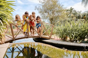 a group of children standing on a bridge over a pond