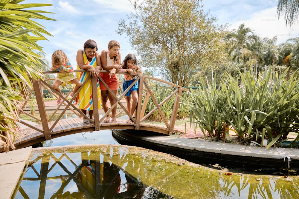 a group of children standing on a bridge over a pond