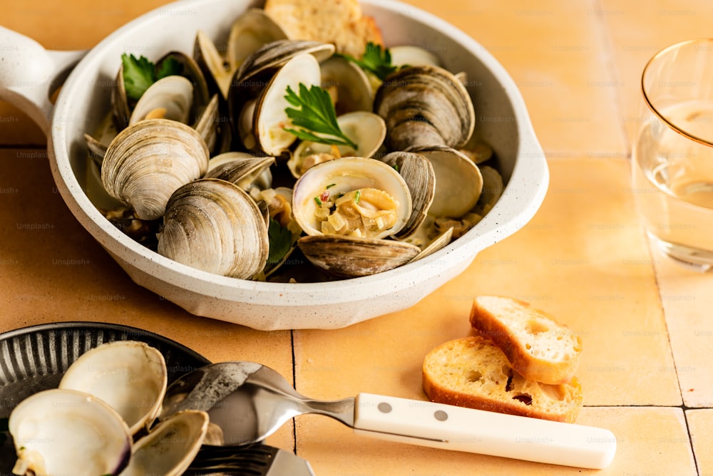 a bowl of clams and bread on a table