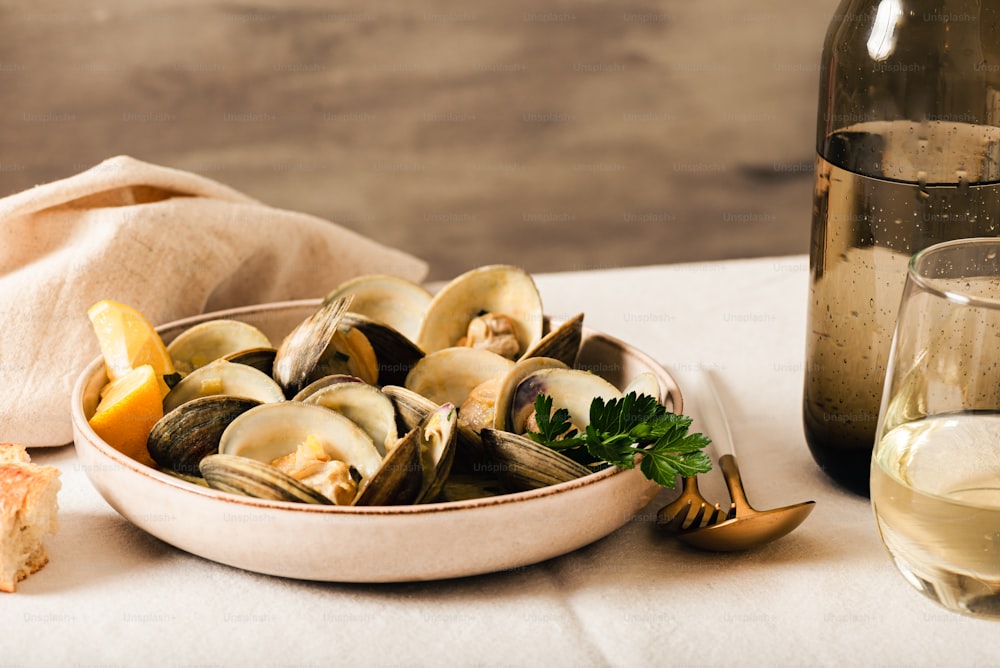 a bowl of mussels next to a glass of wine