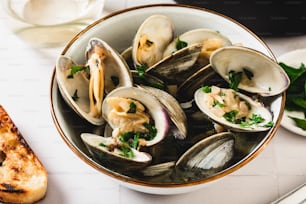 a bowl of clams with a slice of bread on the side