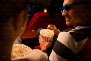 una donna seduta in un cinema con in mano una ciotola di popcorn